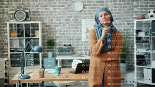 Female Muslim Office Worker In Hijab Standing In Workplace Holding Gles