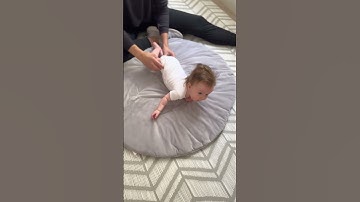 Pediatric physical therapist assisting with roll from tummy to back