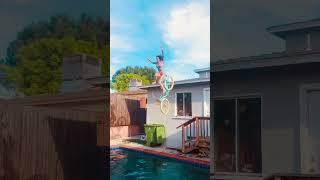 Woman rides beach cruiser bicycle into pool from roof