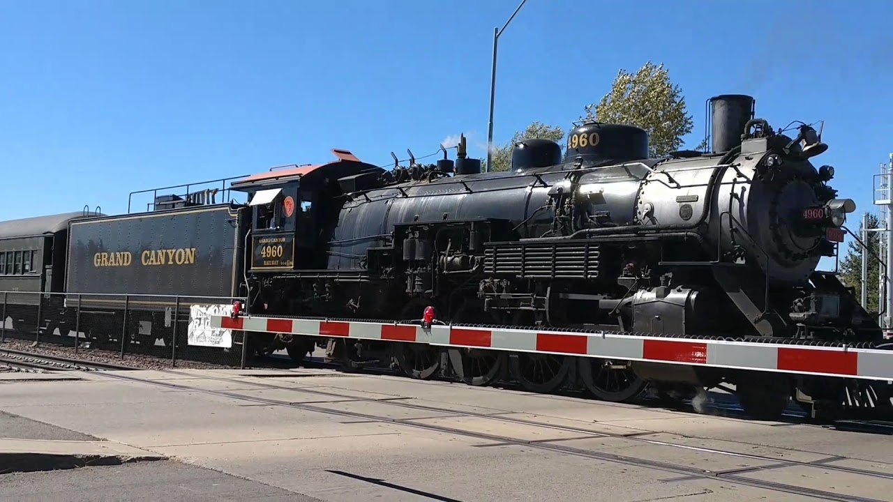 Pedestrian walks in front of train. Grand Canyon railway train arrives in Williams AZ.
