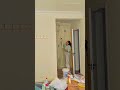 using a long handled roller to apply white paint to the upper interior wall and ceiling corner area
