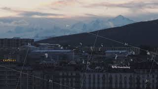 Aerial view of buildings in city and Mont Blanc mountain massive against cloudy sky in distance