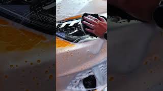 Hand wipes soap suds from car surface