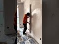 leveling a concrete wall surface using a long aluminum straightedge tool during interior renovation
