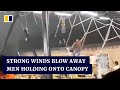 Strong winds in China blow away restaurant staff holding onto canopy