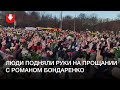 Люди подняли руки с цветами на прощании с Романом Бондаренко