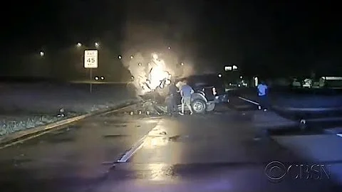 Police officers pull driver from burning car