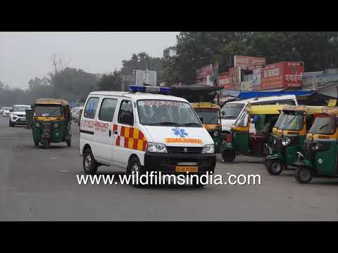 Emergency ambulance moves through traffic on a road in Safdarjung