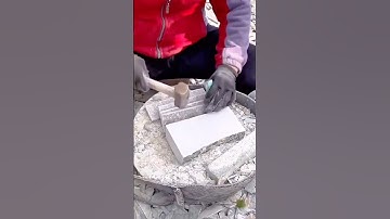 Worker shaping stone block with hammer and chisel for precise edge detailing
