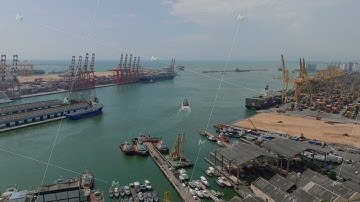 Aerial ascending shot of boats and ships in seaport. Big cranes in international container terminal