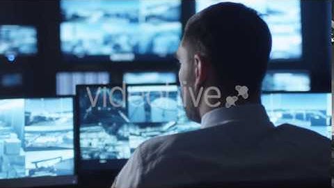 Security Officer is Drinking Coffee while Working on Computer in a Dark Monitoring Room | Stock