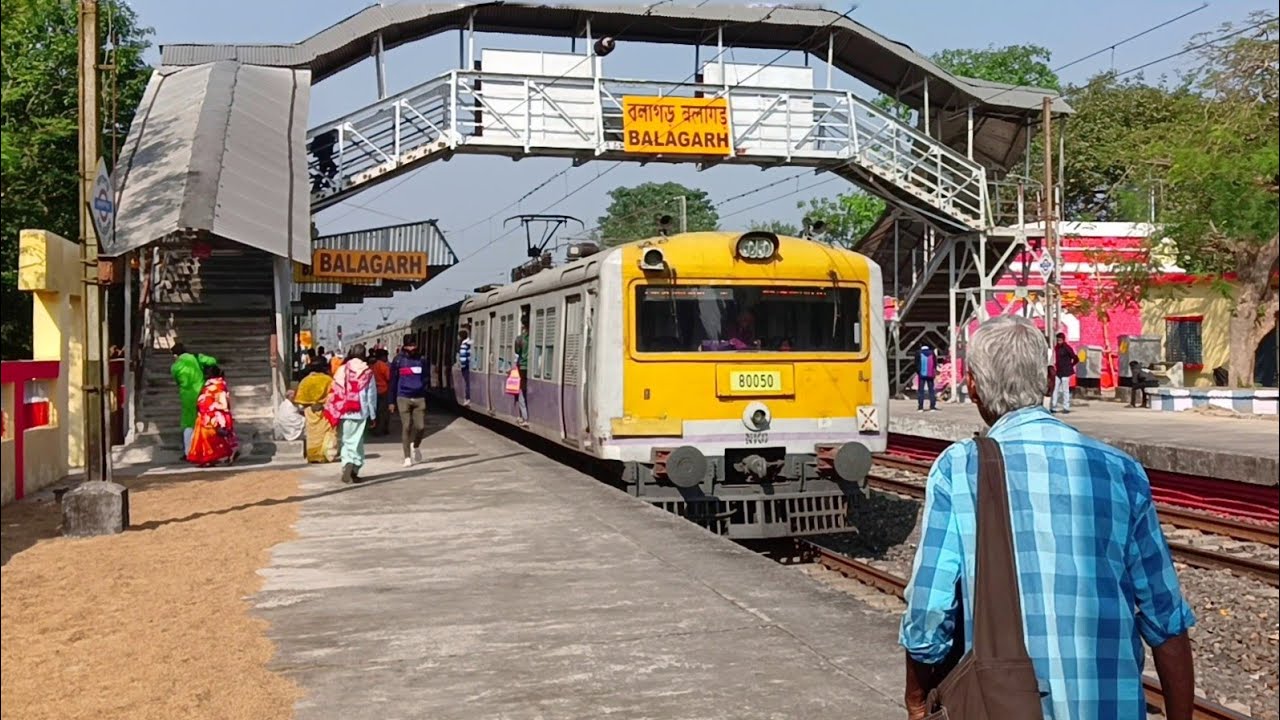 9 coach local train and 12 coach EMU local train arriving and departing a crowded station