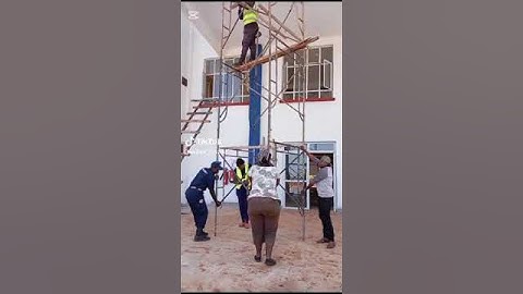 HAZARDOUS:  workers move a mobile scaffolding while a colleague remains on top