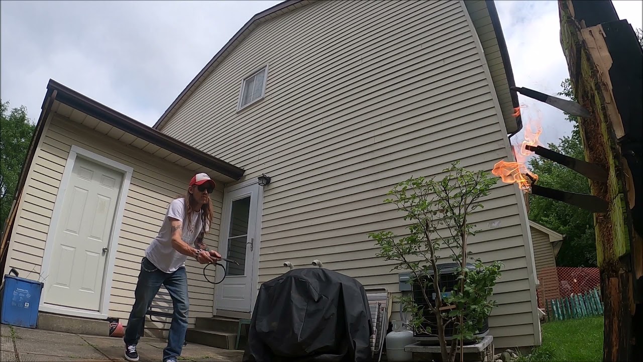 Man Shows Trick Shot By Throwing Knives on Fire At Wooden Board - 1212894