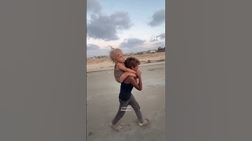 Displaced Palestinian child carries sister as they try to flee Israeli bombardment