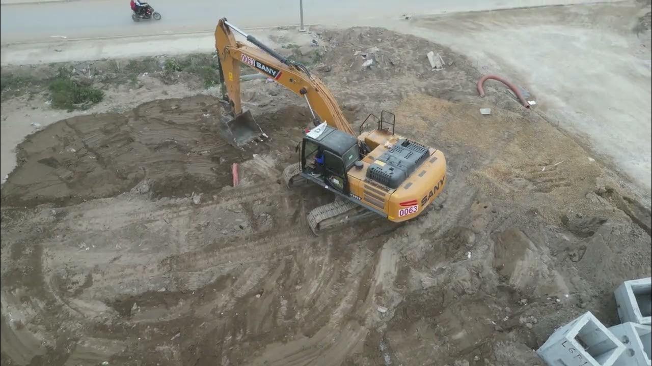 How does an excavator flatten the ground to prepare for building a high
