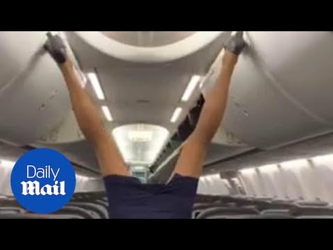 Flight attendant flips upside down to close overhead bins