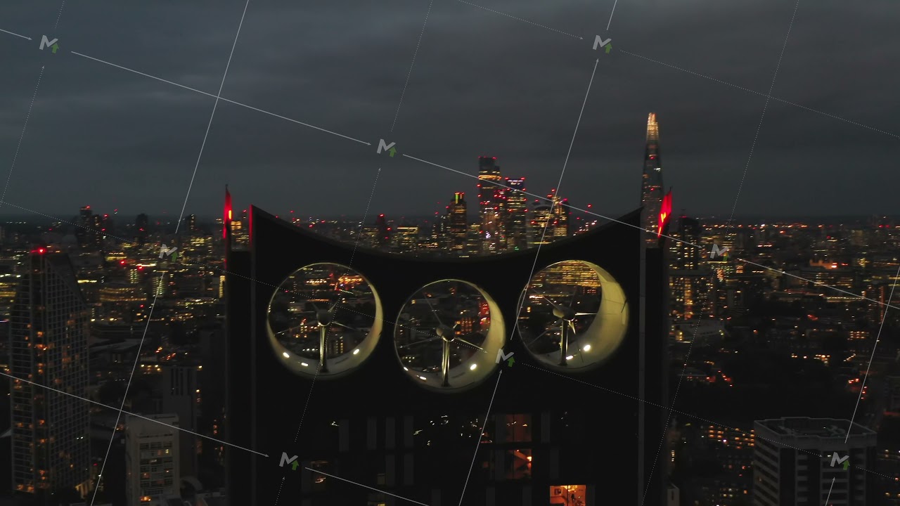 Fly around illuminated top of Strata apartment building. Three wind turbines integrated into house