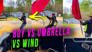 Young Man Gets Swept Away Trying to Hold a Large Umbrella on a Wind Day