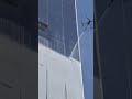 This is the process of spraying soap on the glass of a tall building using the help of a drone.