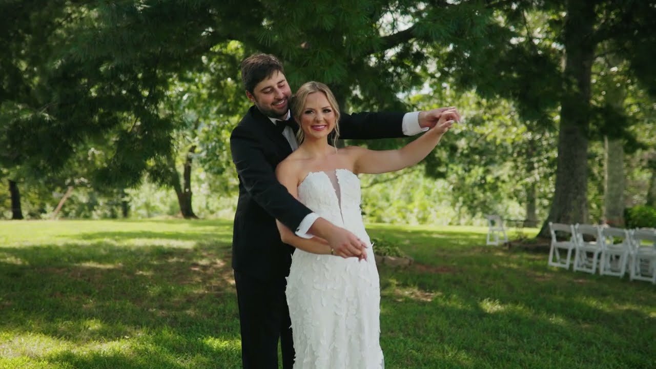 Groom twirling his bride on the lawn under shade trees at White Oaks Vineyard