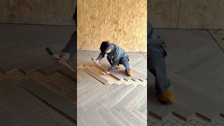 installing herringbone patterned wooden floor panels accurately with hammer and tapping block indoor