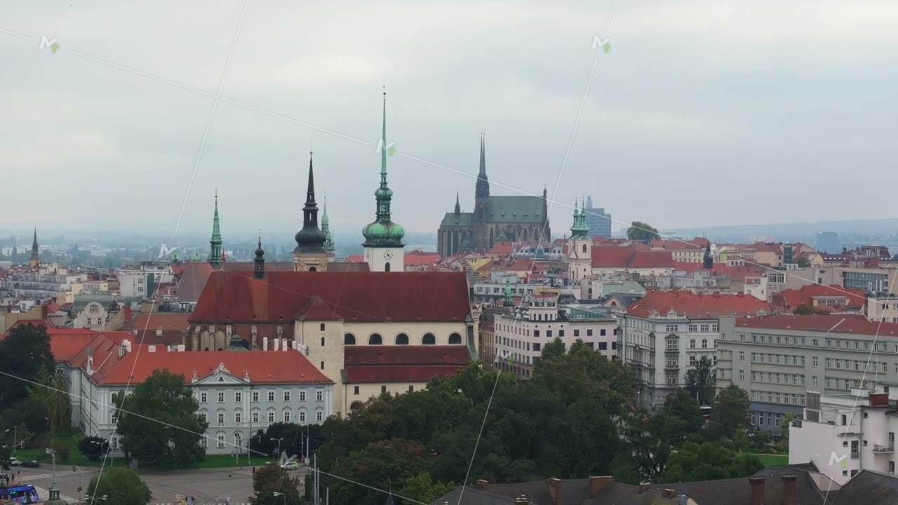 Birds are flying over the city of Brno. The red roofs of the buildings and the Cathedral of St