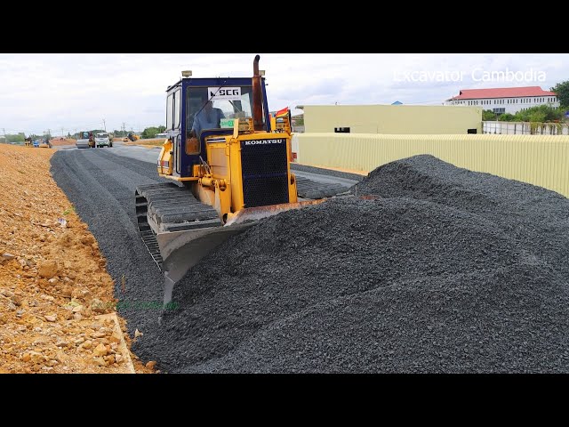 Bulldozer Spreading Gravel Building Foundation New Big Road And Dump Truck Unloading Gravel ... class=