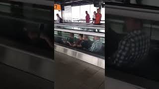 4 Men Rowing On A Moving Walkway At The Airport