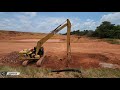 escavadeira fazendo acabamento em caixa de drenagem com Pedra Rachão