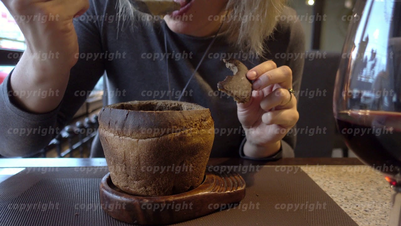 Woman eats soup from a plate made of bread