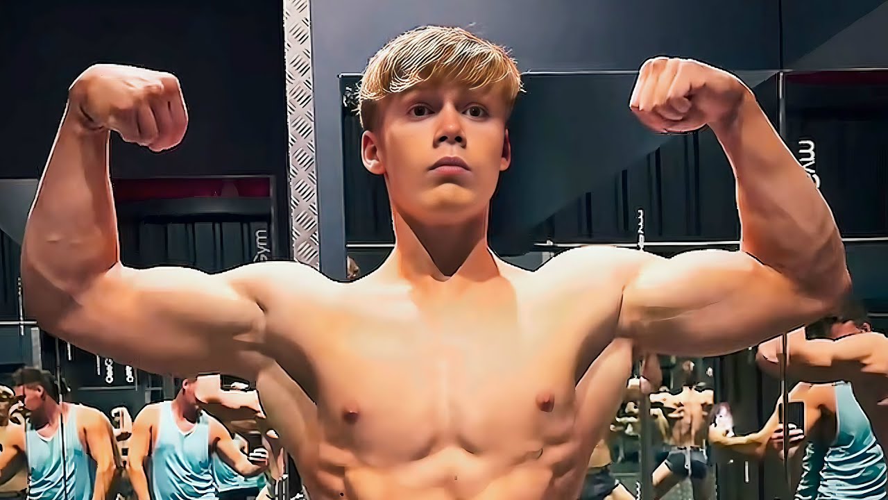 Молодой бодибилдер Джордж Холланд напрягает мышцы