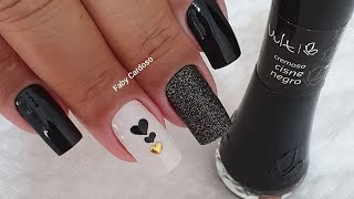 Detalhe das mãos de uma manicure pintando as unhas com um desenho de  esmalte preto