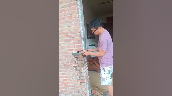 A man puts a brick into a brick wall - repair process
