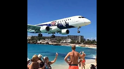 Plane passing just overhead of people on Maho Beach in the Caribbean