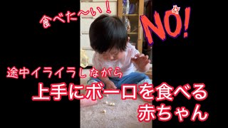 イライラしながら上手にボーロを食べる赤ちゃん