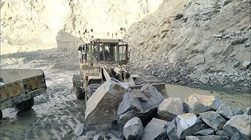 Heavy machine rocks loading in action: caterpillar wheel loader 966F big rocks loading in trolleys