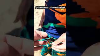 Boy plays with crab on the beach and it latches onto his finger