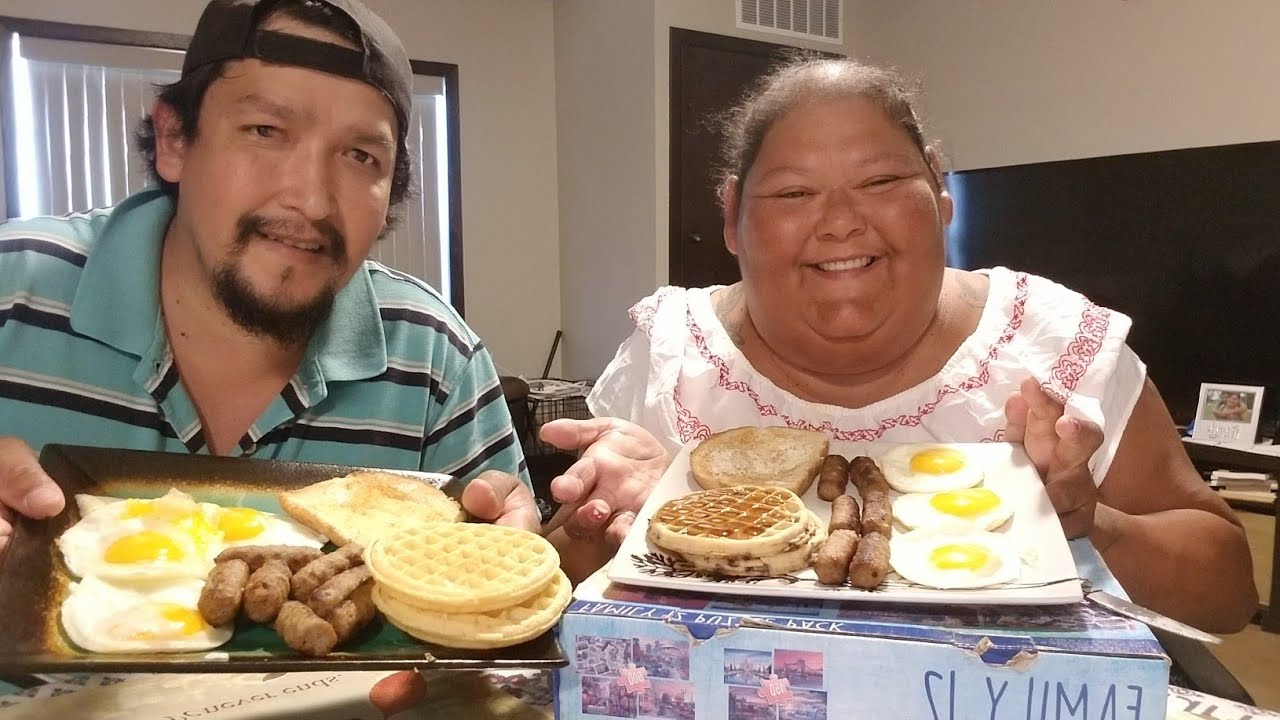 Eating sunny side up eggs/sausages/toast/and waffles/drinking coffee/with my husband