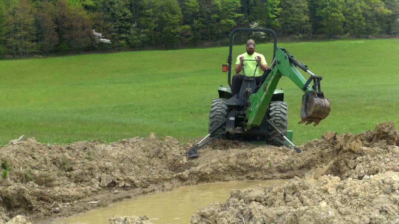 Compact tractor working on pond. John Deere 4200