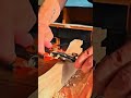 Shaving the curved edge of a wooden furniture leg with a small manual spoke shave tool carefully