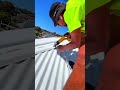 cutting a white corrugated metal roof sheet using an electric power metal shear tool outdoors