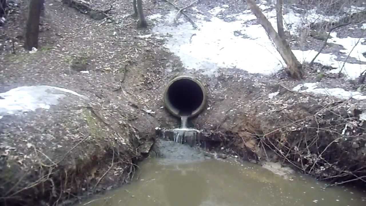 Сброс ливневой воды. Канализационная канава. Выпуск ливневой канализации в реку. Слива в овраг канализационных вод.