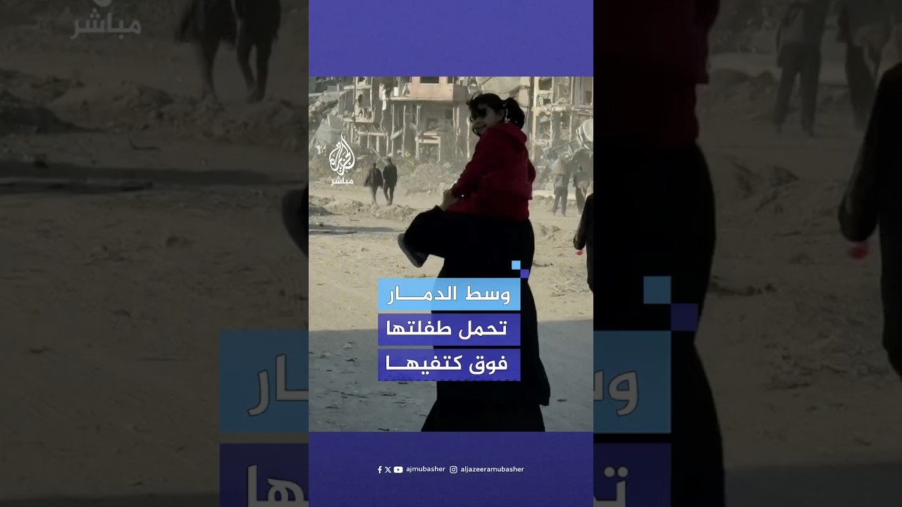 أم فلسطينية تضطر لحمل طفلتها أثناء السير بها وسط مبان مدمرة شمالي قطاع غزة