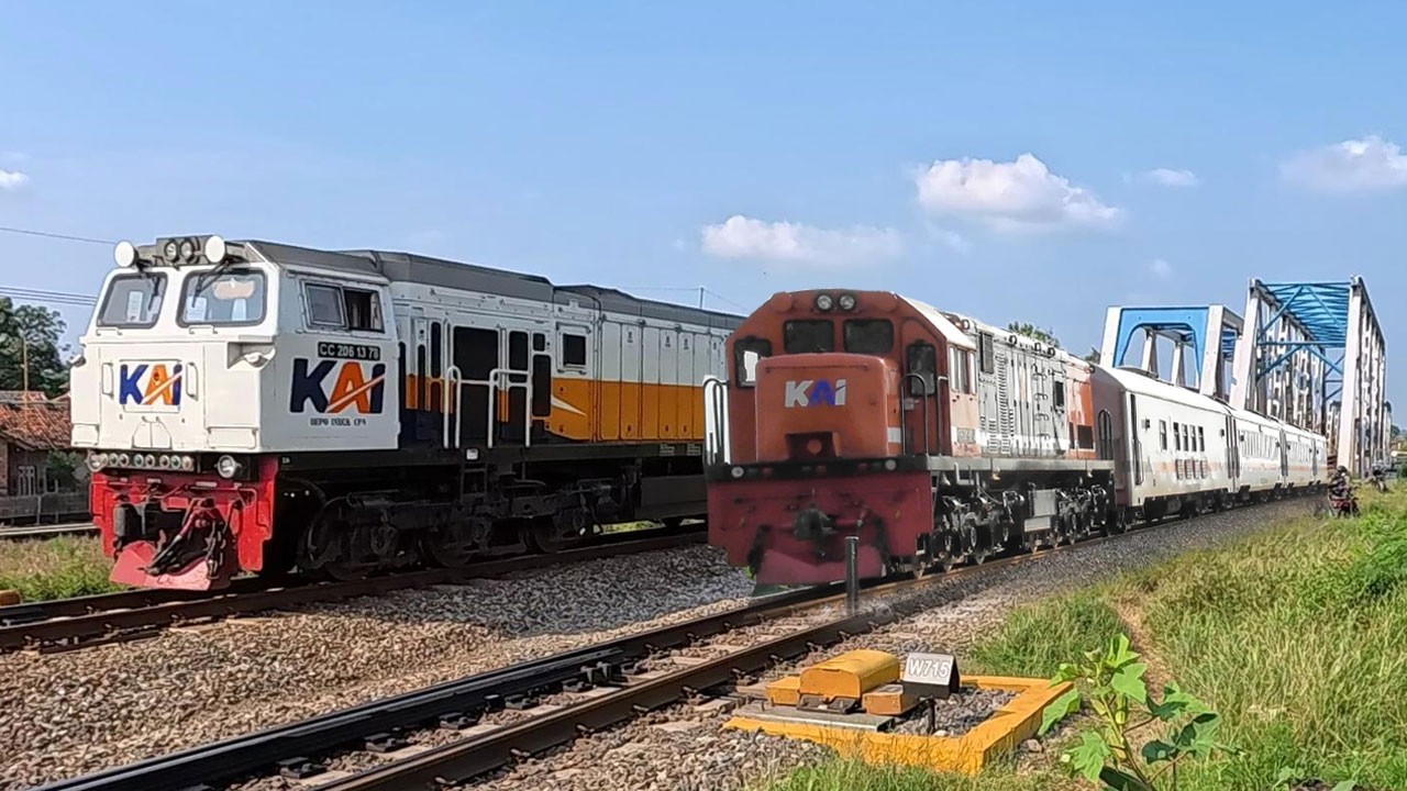 Kereta Api Panjang Lokomotif CC206 CC201 Melaju Cepat Melewati Perlintasan Jembatan