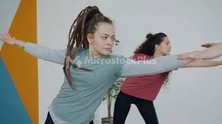 Good-Looking Girl Hipster Training In Sports Center Doing Yoga With Group Of Women
