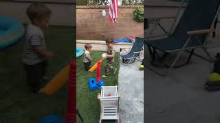 Boy hits baseball from batting tee and ball hits little brother on his head/face