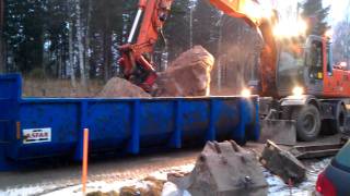 Hitachi EW160 lastar en sten på lastväxlarflak.