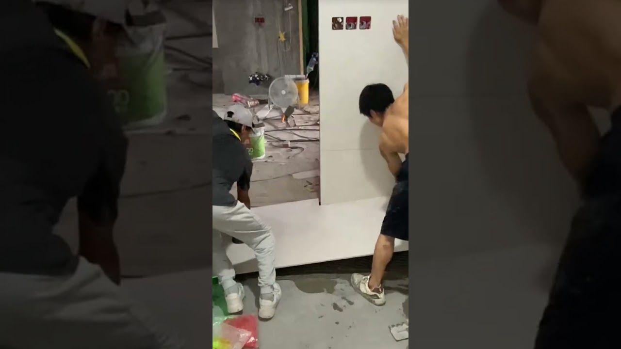 the process of installing large plain white ceramic tiles on the floor of the room 