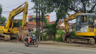 nyamperin dua excavator parkir di pinggir jalan raya yang rusak